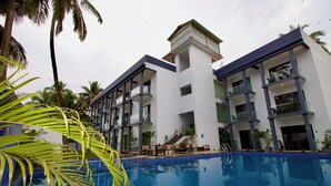 A modern hotel with a swimming pool, balconies, and palm trees. - The Upper House By Mystical Views (Morjim)