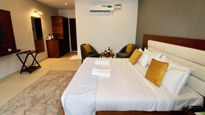 A hotel room with a large bed, two armchairs, a small table with a bottle and glasses, and an air conditioning unit on the wall. - The Upper House By Mystical Views (Morjim)
