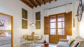 A cozy living room with a sofa, a dining table with chairs, and a large wooden door. - Rustic Chic Living4Malaga (Málaga)