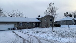 A residential area with a stone house, a garage, and a snow-covered yard. - Manotick waterfront property. Walking distance to pubs restaurants. groceries.
 (Ottawa)