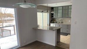 A modern kitchen with a large island, light wood flooring, and a view of a snowy outdoor area. - Manotick waterfront property. Walking distance to pubs restaurants. groceries.
 (Ottawa)