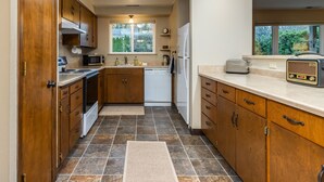 A kitchen with wooden cabinets, a microwave, a toaster, and a window with a view of greenery.