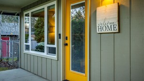 A house with a yellow front door, a welcome home sign, and a porch with a light fixture.