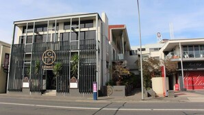 Un edificio moderno con un logo destacado, un acceso con portón y una señal visible para un restaurante.