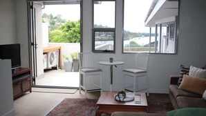 Una sala de estar con sofá, mesa de centro, televisor y vistas amplias por las ventanas.
