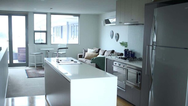 Una cocina moderna con una isla central, electrodomésticos de acero inoxidable y vistas al exterior.