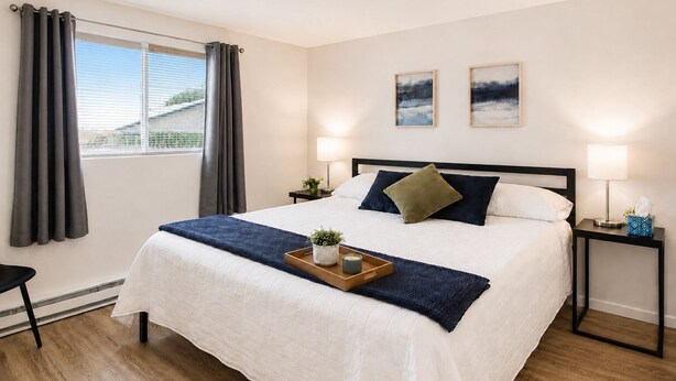 Een hotelkamer met een bed, twee nachtkastjes, een raam met gordijnen en twee aan de muur hangende schilderijen.