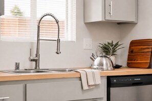 A kitchen with a modern faucet, a kettle, a wooden cutting board, and a dishwasher. - Full kitchen - Cozy 2 BR with King bed - Hospital & Hanford super close. (Richland)