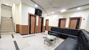 A reception area with a staircase, a black leather sofa, a glass coffee table, and wooden doors with a 'STAY ONLY' sign. - Wisma Saranani (Kendari)