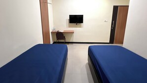 A small, clean room with two single beds, a desk with a chair, a flat-screen TV mounted on the wall, and a wardrobe. - Wisma Saranani (Kendari)