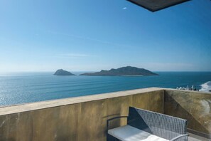 A balcony with a view of the sea and distant islands.