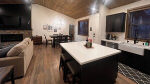 Una cocina moderna con una isla central, techo de madera y un área de comedor con sofá y sillas.