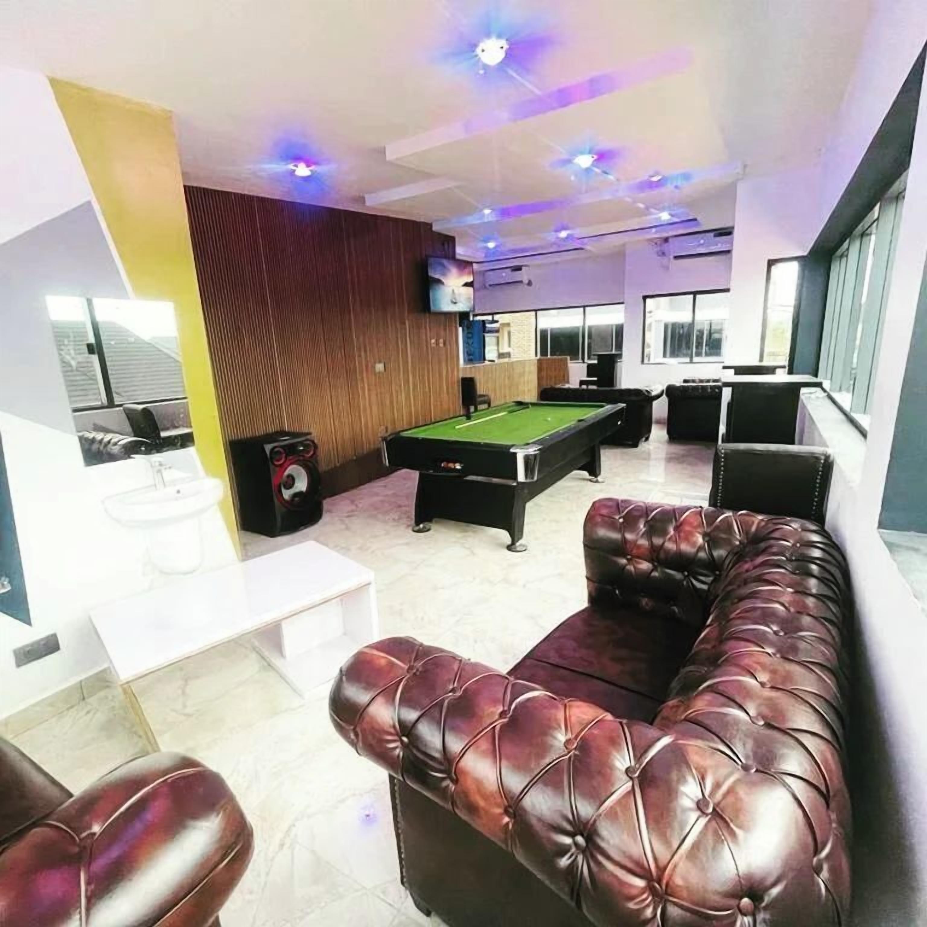 A billiards room with a pool table, leather sofas, and a TV mounted on the wall.