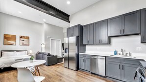 A modern kitchen with grey cabinets, stainless steel appliances, and a white countertop.