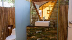 Un baño con mampara de vidrio, inodoro blanco, lavabo con encimera de madera y zona de ducha.