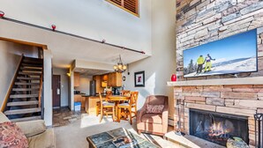 A spacious living room with a fireplace, a dining area, and a kitchen in the background. - Breck Ski-In/Ski-Out Condo with Resort Amenities (Breckenridge)