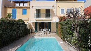 Ein zweistöckiges Gebäude mit Schwimmbad, Balkon und einer Terrasse mit Gartenmöbeln.