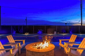A pool area with a fire pit in the center, surrounded by wooden chairs. - Updated Oasis w/ Private Yard, BBQ & Hot Tub (Lake Havasu City)