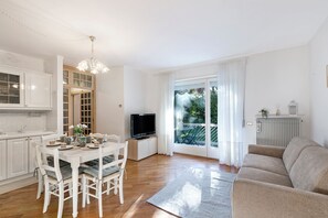 Uma sala de estar moderna com área de jantar, televisão e sofá.