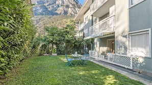 A hotel with a balcony, a grassy lawn, and a mountain view. - Riva's Garden Home (Riva del Garda)