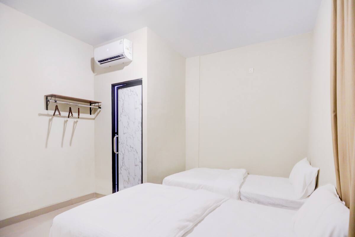 Habitación de hotel con dos camas, un armario, perchero y aire acondicionado.