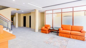 Un vestíbulo espacioso con una escalera, un sofá grande color naranja y una alfombra estampada.