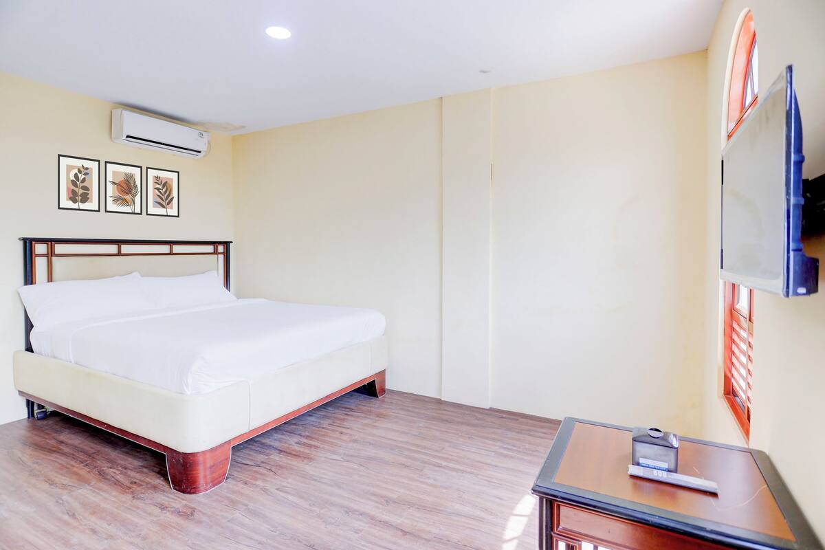 Habitación de hotel con cama, aire acondicionado, televisor de pantalla plana y cuadros en la pared.