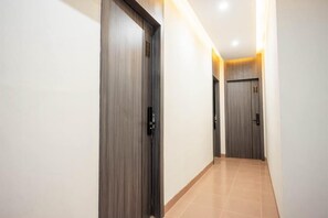 A corridor with wooden doors and a tiled floor. - Collection O Nagoya Near Nagoya Hill Mall Formerly Sedago Inn (Batam)
