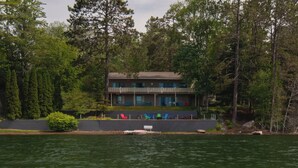 En tvåvåningsbyggnad med en balkong, omgiven av tät skog.