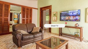 Ein Wohnzimmer mit einem braunen Ledersofa, einem Glastisch und einem an der Wand montierten Fernseher, der eine Speisekarte zeigt.
