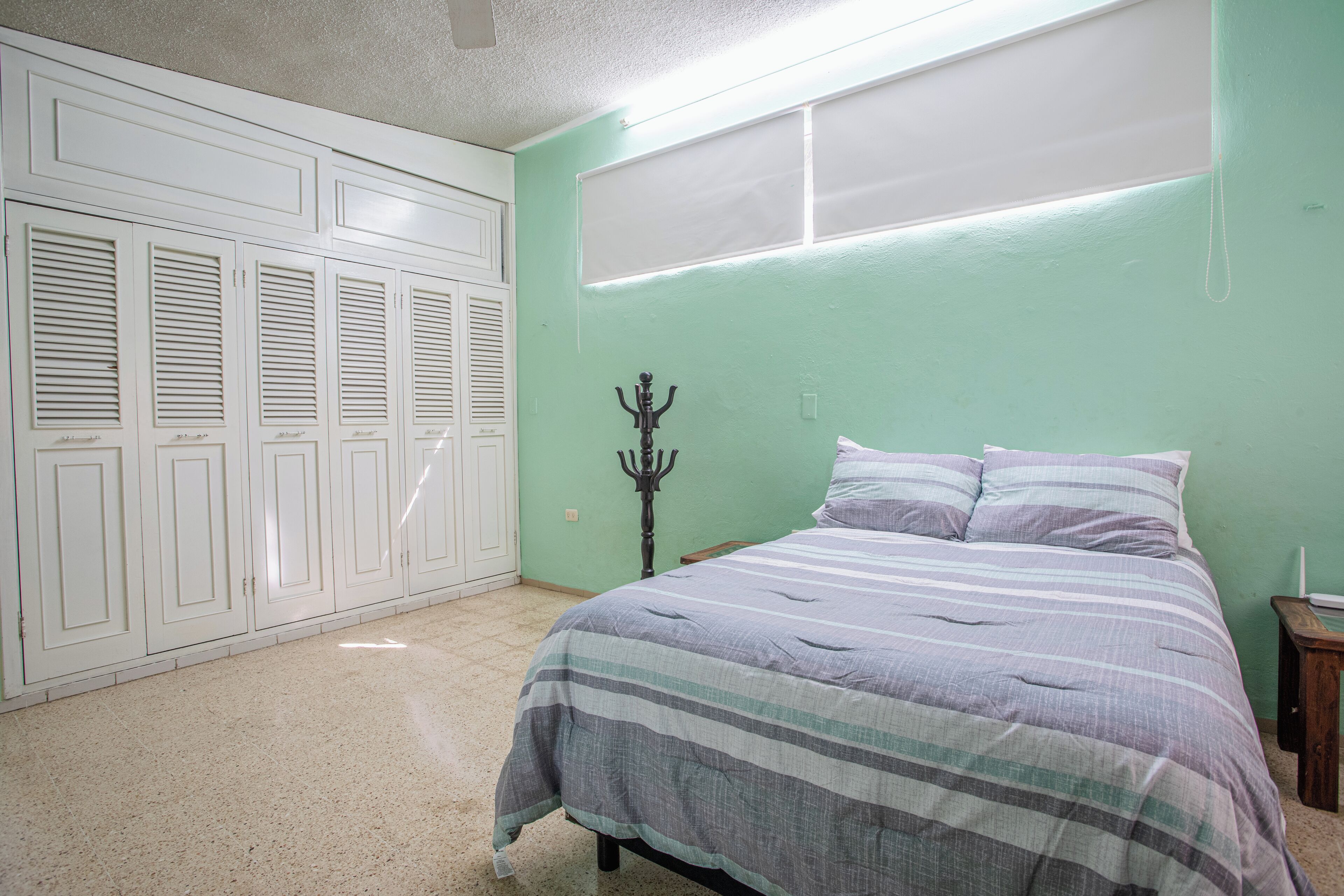 A bedroom with a bed, a wardrobe, and a coat rack.