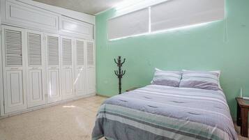 A bedroom with a bed, a wardrobe, and a coat rack.