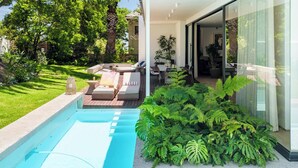 A modern outdoor pool area with lounge seating and lush greenery.