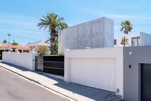 A modern building with a garage door, a concrete wall, and a palm tree in the background.