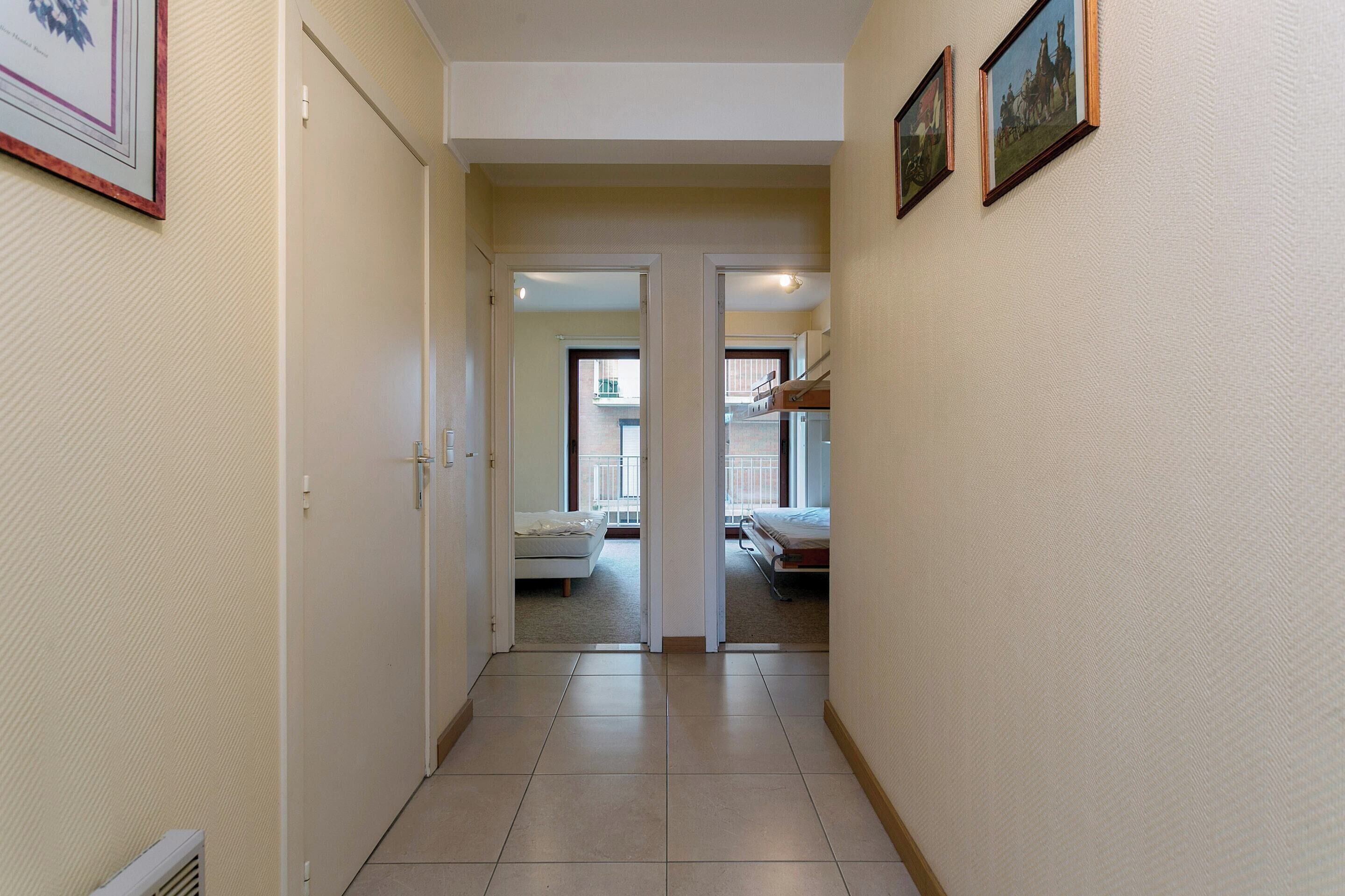 A corridor with doors leading to bedrooms, each with a bed and a window.