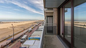 A balcony with a view of a beach and a road with vehicles. - Apartment in Blankenberge Near the Beach (Blankenberge)