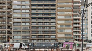 A multi-story building with balconies, a storefront, and construction materials in the foreground. - Apartment in Blankenberge Near the Beach (Blankenberge)
