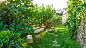 A lush garden with a stone wall, a wooden bench, and a small table with a chair. - Nice apartment in Casal Velino with swimming pool (Casal Velino)