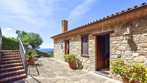 A stone building with a tiled roof, a staircase leading to a deck, and potted plants. - Nice apartment in Casal Velino with swimming pool (Casal Velino)