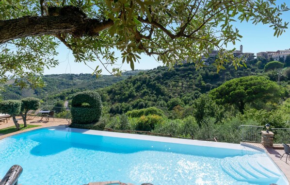 Una piscina con vista a un paisaje verde exuberante y un horizonte urbano lejano.
