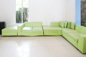 Un sofá modular verde en una habitación luminosa con un ventanal grande.