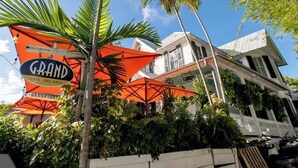 A building with a sign that reads "GRAND cafe key west" and a palm tree in the foreground. - Sailfish Suite on Duval (Key West)