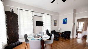 A modern living room with a dining area, featuring a wooden floor, white walls, and contemporary furniture. - Sailfish Suite on Duval (Key West)