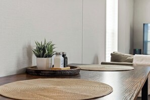 A wooden table with woven placemats, a potted plant, salt and pepper shakers, and a tray.