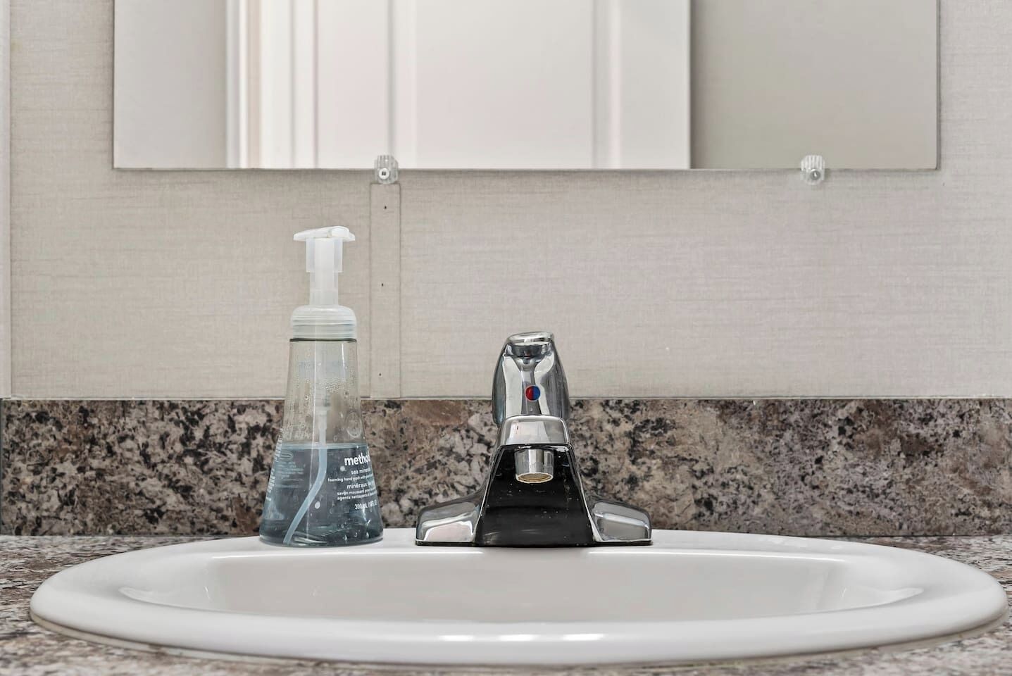 A bathroom sink with a faucet, a soap dispenser, and a mirror above.