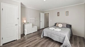 Une chambre à coucher avec un lit, une commode, une table de chevet et une porte.