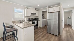 Une cuisine moderne avec des meubles blancs, un réfrigérateur en acier inoxydable, un four et un four à micro-ondes.