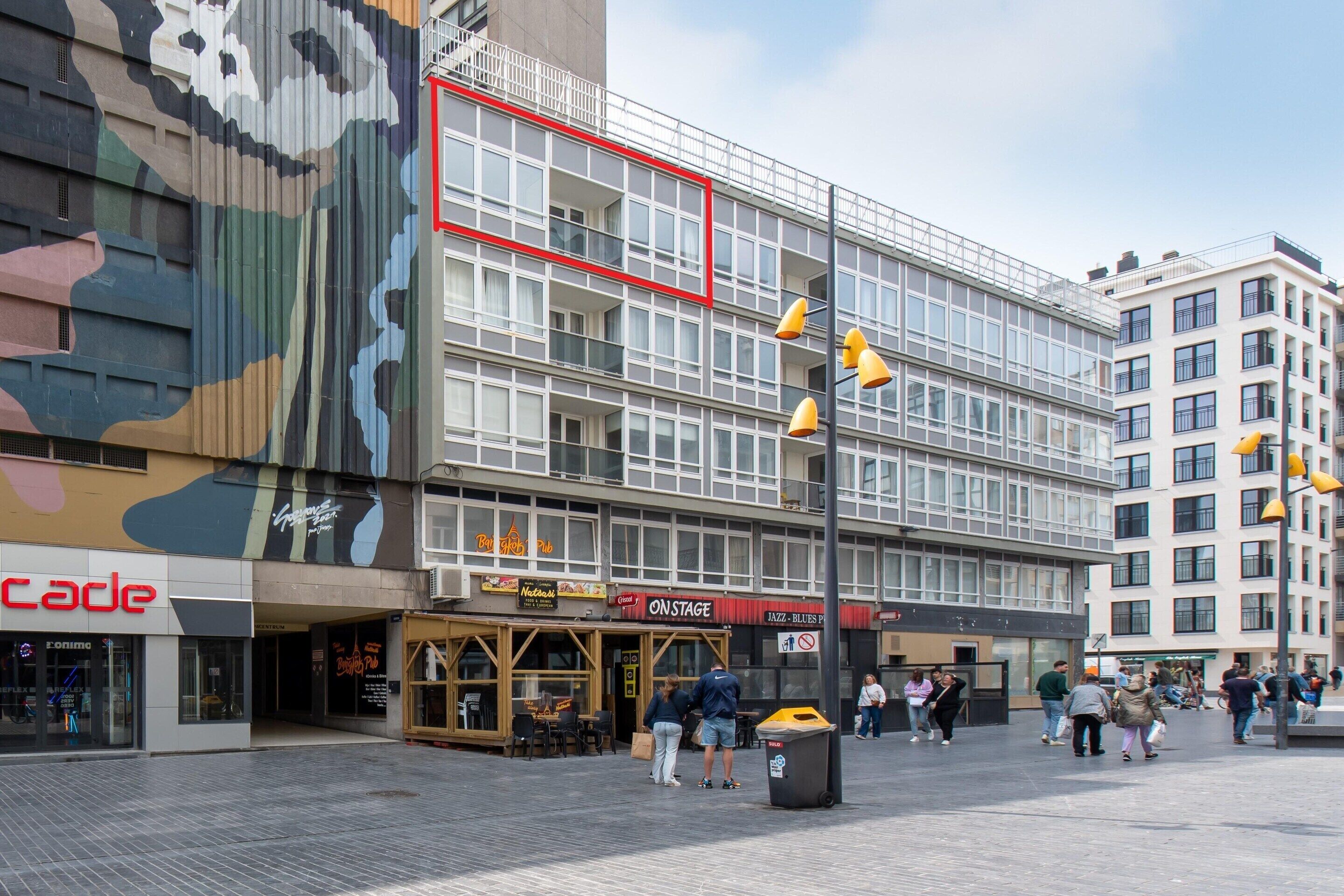 Un edificio de varios pisos con fachada moderna, que cuenta con una cafetería y un club de jazz en la planta baja.