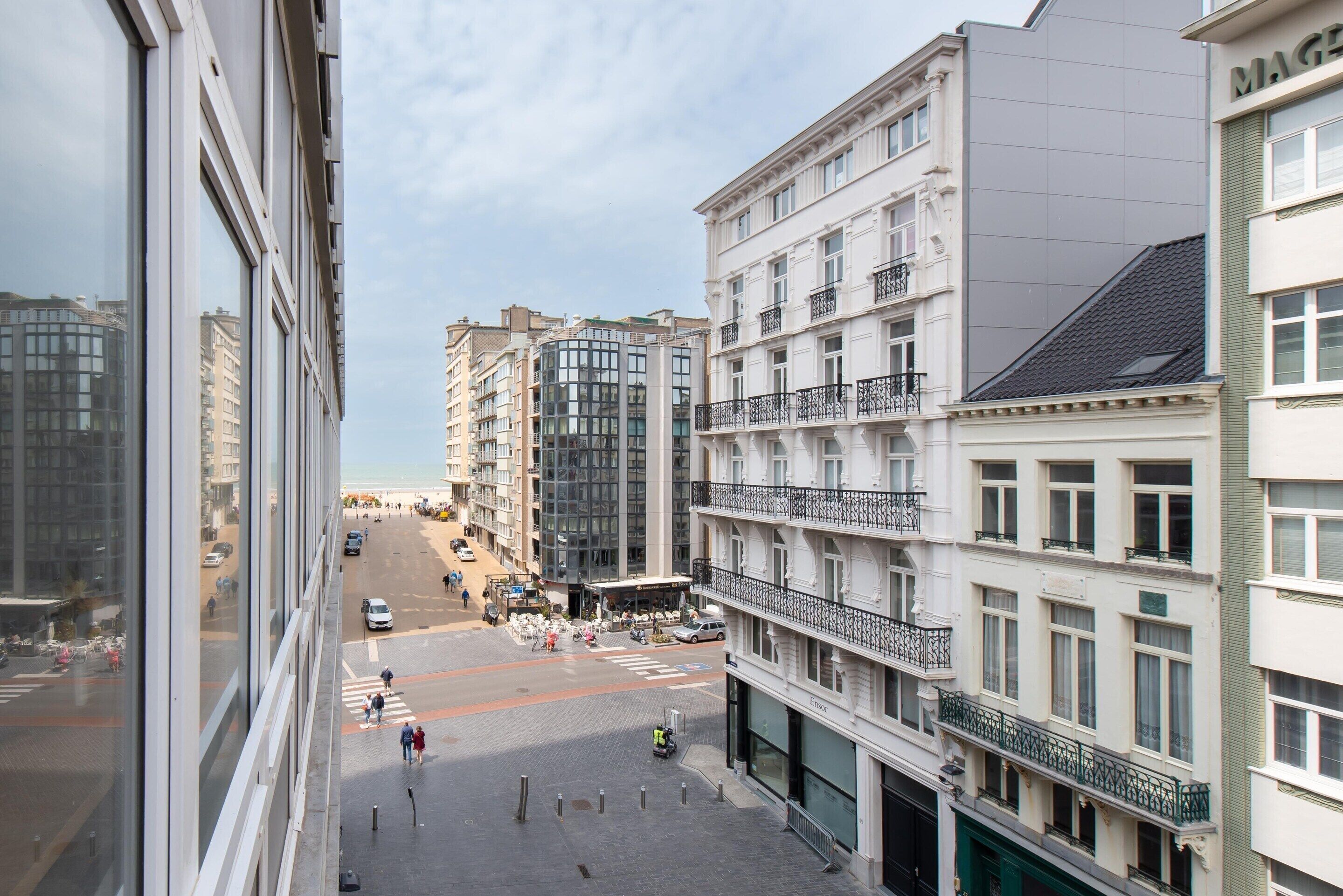 Ein mehrgeschossiges Gebäude mit Balkonen, Blick auf eine Straße und einer Fußgängerampel.