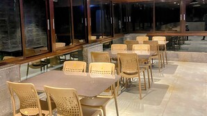 A spacious indoor dining area with high ceilings and large windows, providing ample natural light. - Hotel Om Palace (Mahabaleshwar)